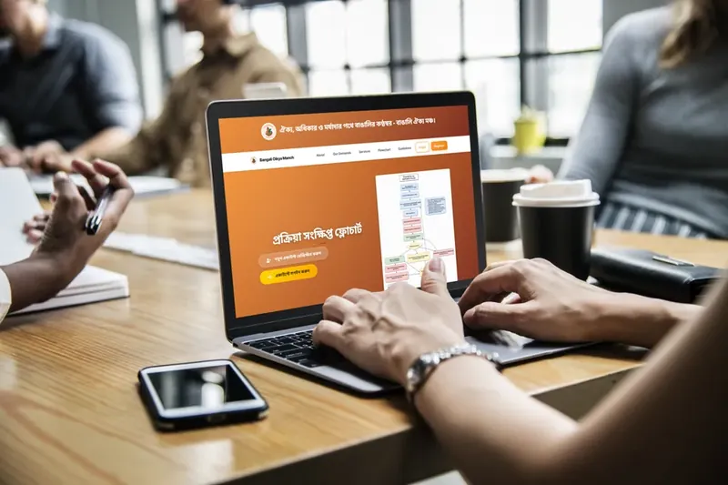 The web app's Bengali home page open on a laptop