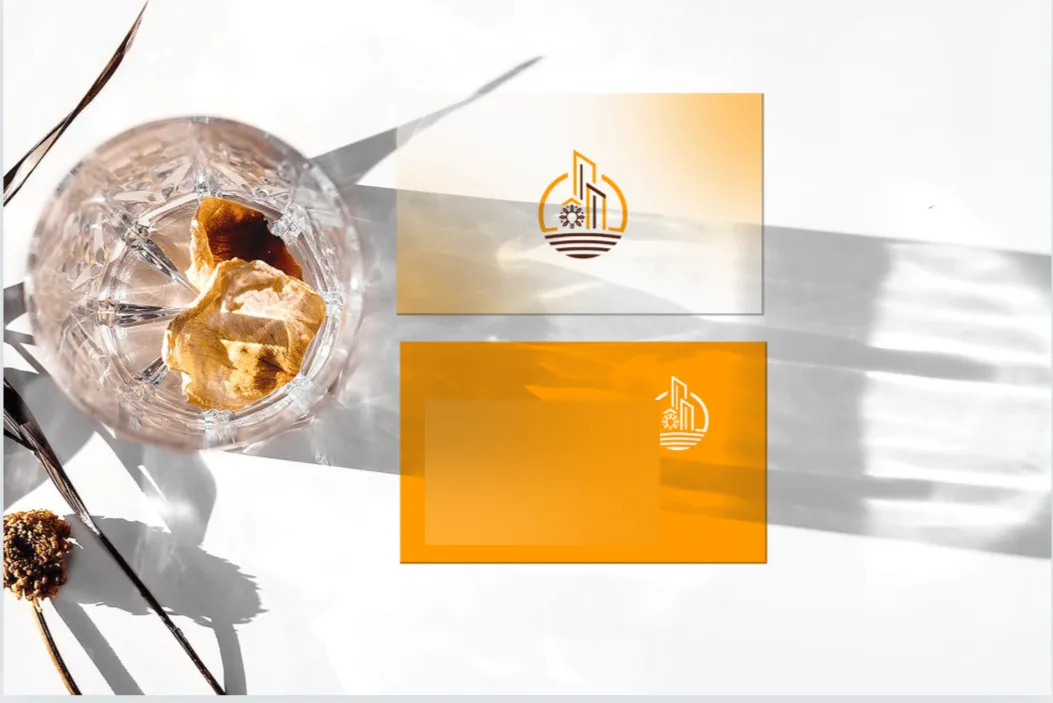 Mockup: two stationery cards, one with the logo on a fading amber background and one in amber with the logo in white, beside a crystal glass; the placeholder contact details are blurred